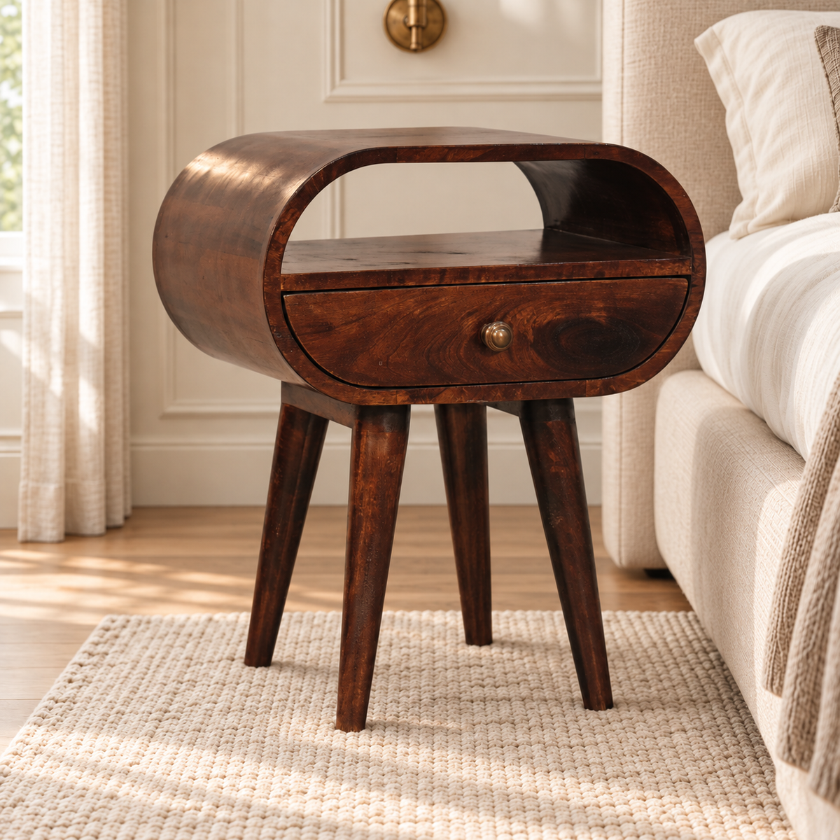Walnut-finish bedside table showing its curved right side, open shelf, single drawer and tapered wooden legs.
