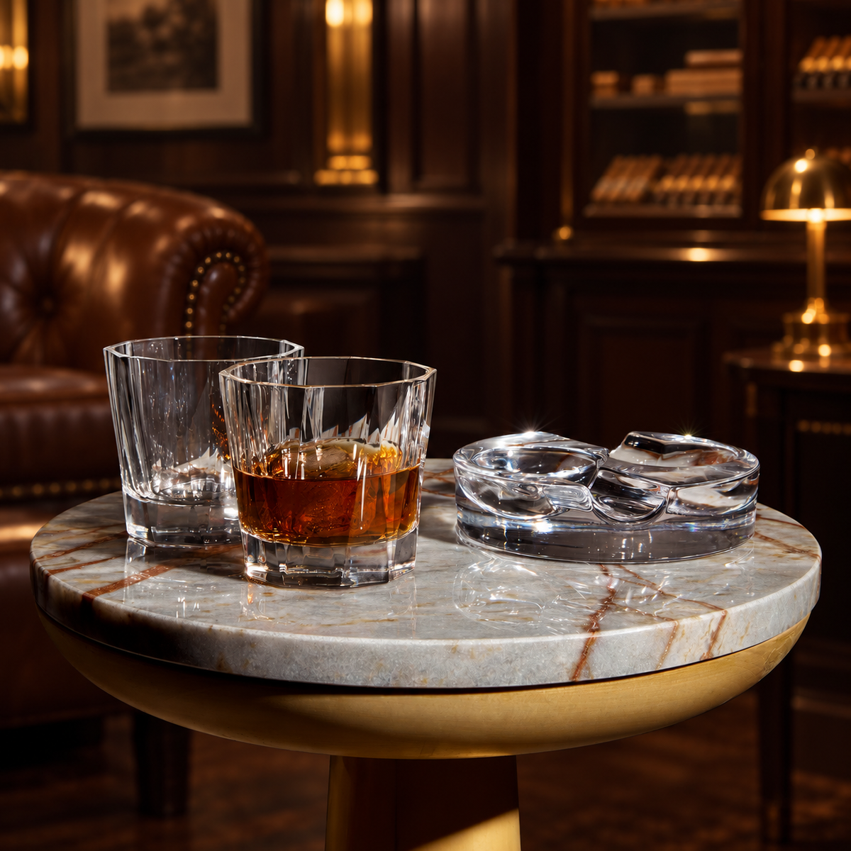 Heavy crystal cigar ashtray beside whiskey glasses on a marble table in an elegant cigar lounge
