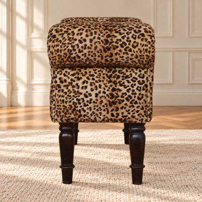 End view of the leopard-print velvet bench, showing its rounded upholstered arm and walnut-finish turned legs.
