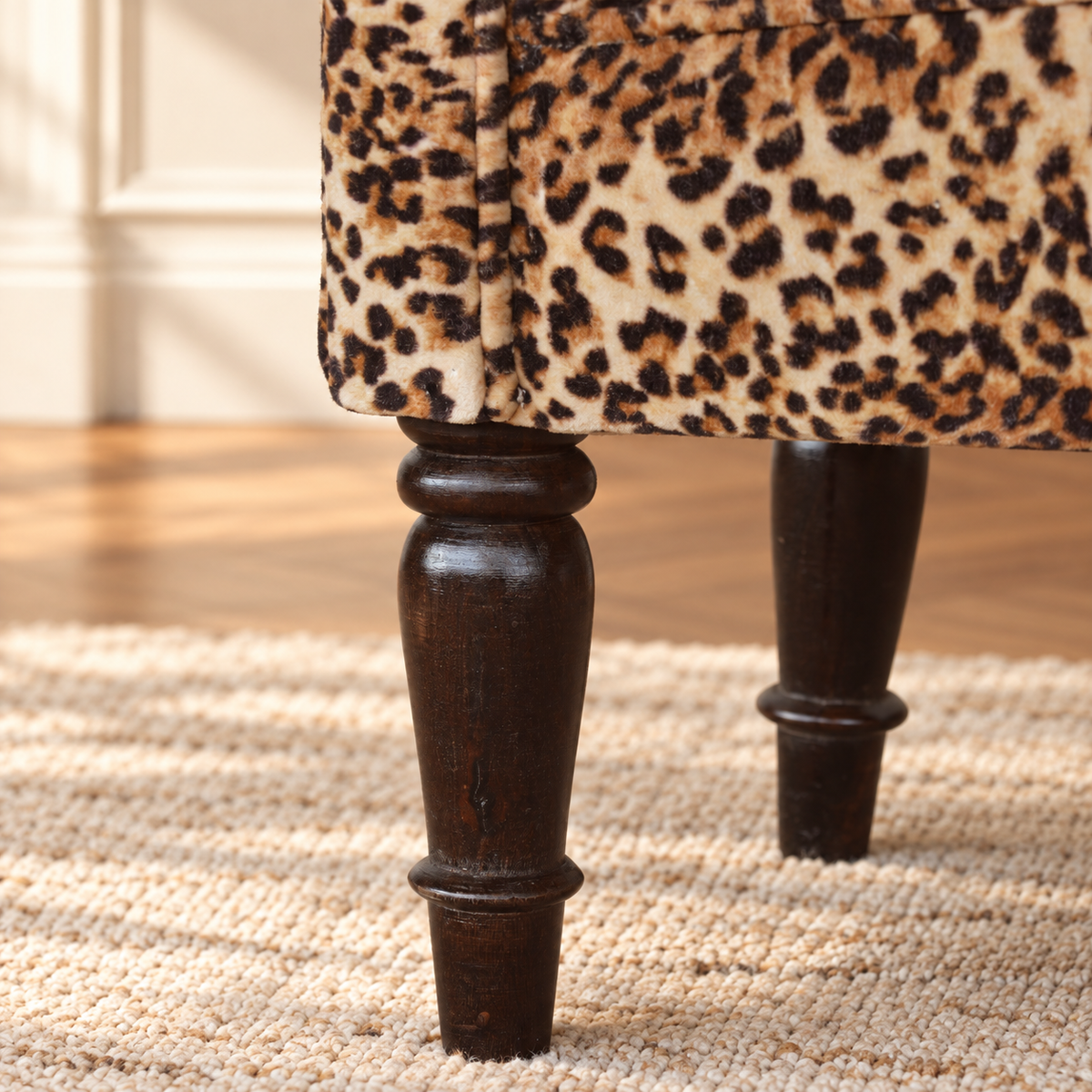 Close-up of walnut-finish turned wood legs beneath the bench’s leopard-print velvet upholstery.