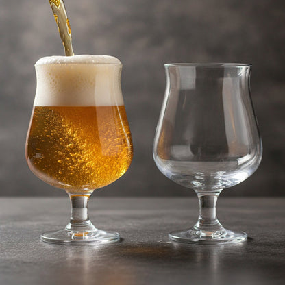 Belgian ale pouring into a stemmed beer glass beside a matching empty glass